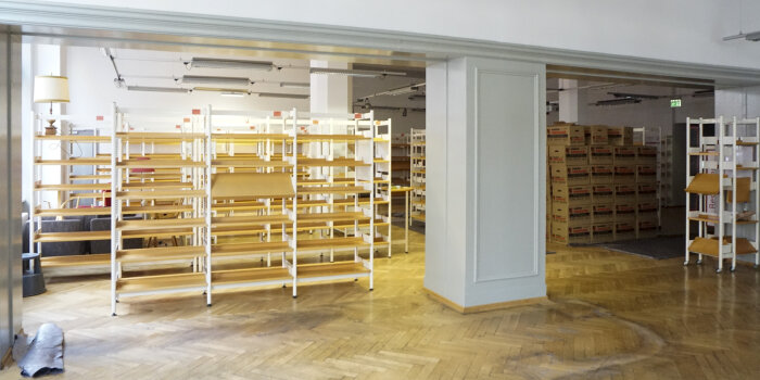 Blick in einen Raum mit leeren Bücherregalen und abgenutztem Parkettboden