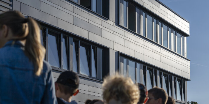 Mehrere Kinder in Rückansicht vor einer Hausfassade. 