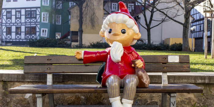 Eine farbige Sandmann-Figur sitzt auf einer Bank 