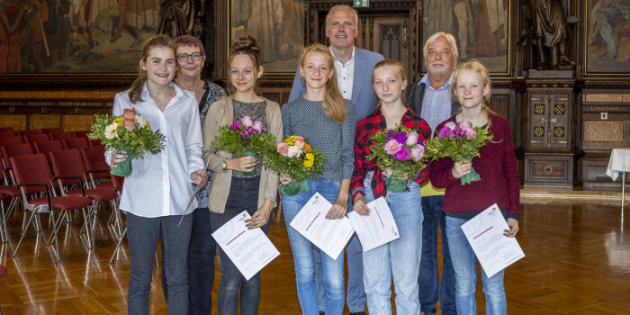 Drei Erwachsene und fünf Kinder stehen in einer Gruppe zusammen.