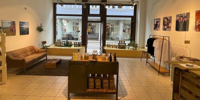 Foto: Pop-up-Store F11 März 2022 © Stadtverwaltung Erfurt Ladenlokal mit Theke, Präsentationstisch, Kleiderstange und Couch.