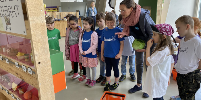 Eine Frau zeigt mehreren Kindern etwas auf einer Tafel.