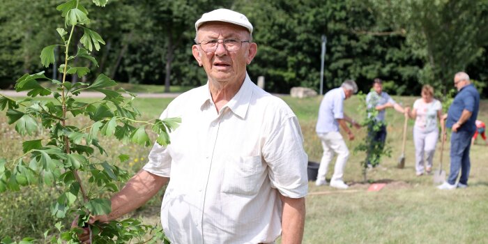 Foto: Roland Büttner im Sommer 2021 © Karina Hessland-Wissel ein älterer Mann steht an einem jungen Baum