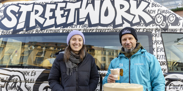 Eine Frau und ein Mann stehen vor einem Bus, auf dem das Wort Streetwork steht.