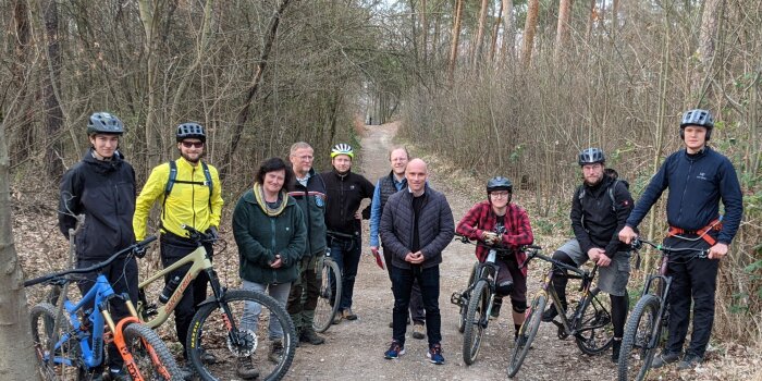 Mehrere Personen stehen mit ihren Fahrrädern im Wald.