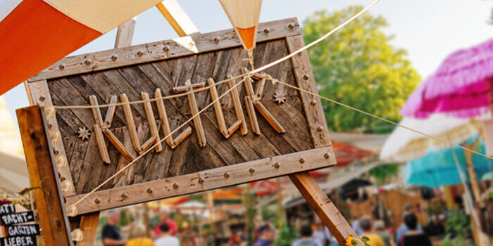 Foto: Kreativgarten Egapark © SWE Stadtwerke Erfurt GmbH ein Holzzaun und das Schild "Kultur", im Hintergrund mehrere Menschen