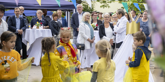 Kinder führen ein Schauspiel auf. Viele Erwachsene sehen zu. 