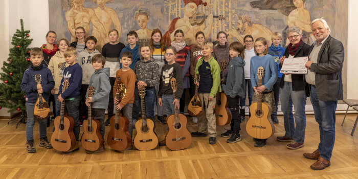 Gruppenfoto mit mehreren Kindern, die zum Teil Gitarren und Zupfinstrumente halten, und vier Erwachsenen