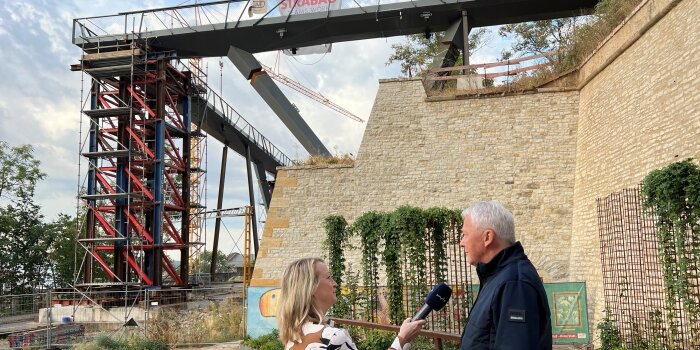 Zwei Personen stehen vor einer Festungsmauer mit einer Brücke