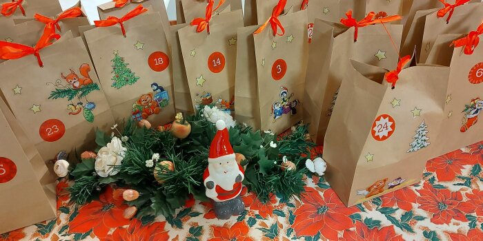 Geschenktüten mit weihnachtlichen Motiven stehen auf einem Tisch. 