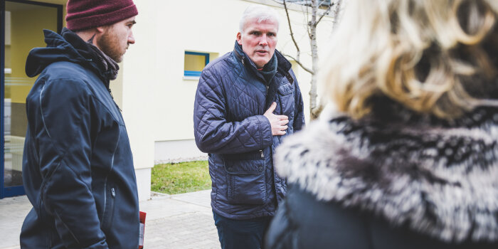 Drei Menschen vor einem Gebäude