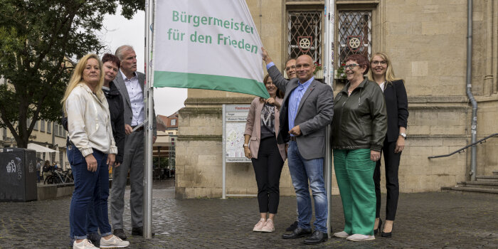 Mehrere Personen stehen neben einer grün-weißen Flagge