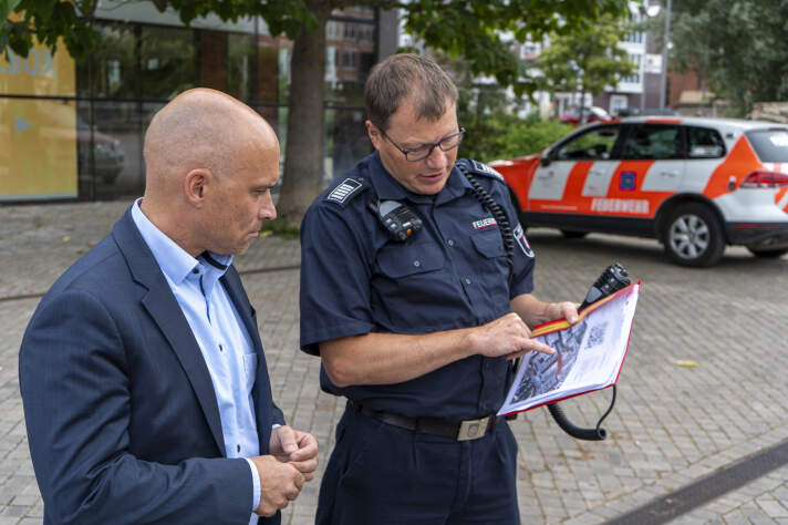 Zwei Männer unterhalten sich. Einer zeigt auf einer Karte etwas.