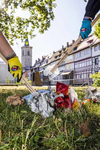 zwei Menschen picken Müll mit Holzgreifern