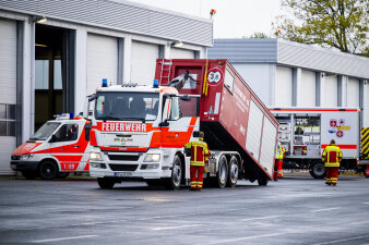 Ein Feuerwehrwagen lädt einen Container ab.