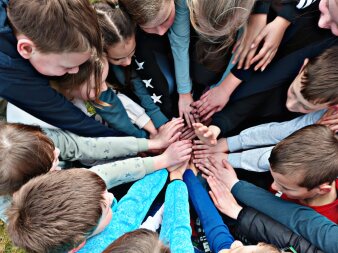 Mehrere Kinder legen Ihre Hände übereinander.