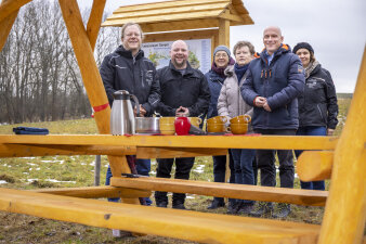 sechs Personen stehen an einer Holzschänke