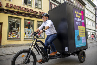 ein Mann fährt auf einem Fahrrad mit Leuchtreklameaufsatz