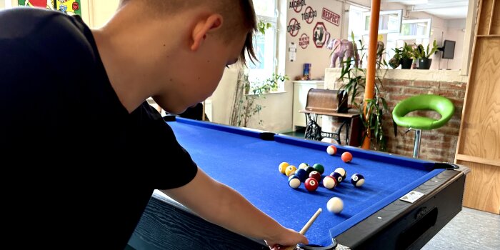 Ein Junge spielt Billard.