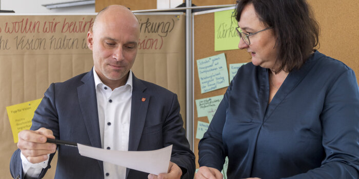 Ein Mann und eine Frau sind im Gespräch. Beide gestikulieren dabei. 