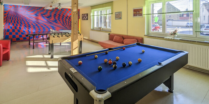 ein bunt gestalteter Raum mit Billiardtisch, Kicker und Tischtennisplatte