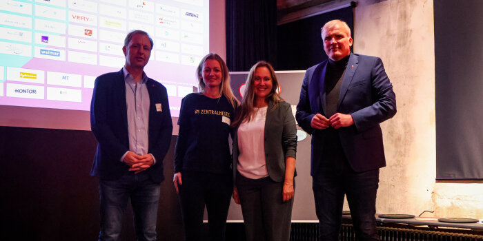 Ein Gruppenfoto aus vier Personen, die nebeneinander stehen. 