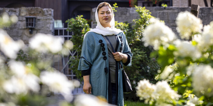 Eine Frau mit Schleier und traditionellem Gewand steht in einem Garten. 