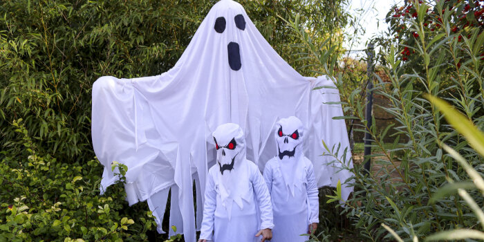 Zwei als Gespenst verkleidete Kinder stehen vor einer großen Figur ind Form eines Gespenstes. 