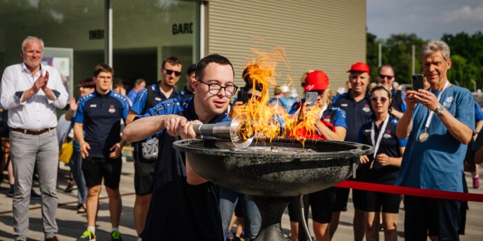 Ein Mann entzündet ein olympisches Feuer mit einer Fackel.