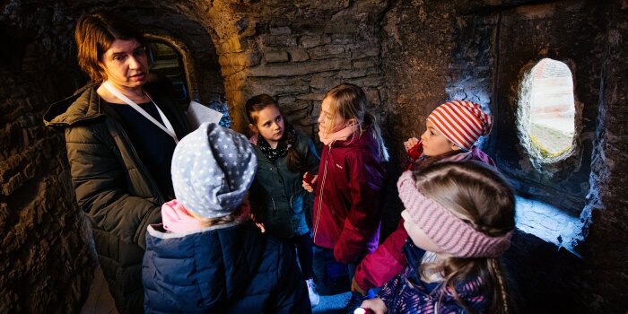 eine Erwachsene und fünf Kinder stehen im Mauergang einer Festung