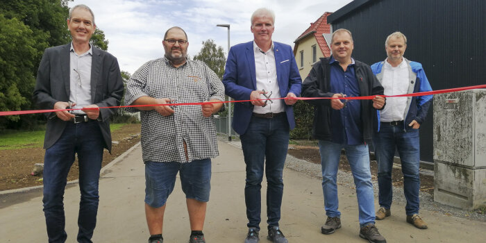 fünf Männer schneiden ein rotes Band durch