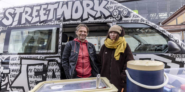 zwei Menschen stehen vor einem Kleinbus mit Aufschrift "Streetwork"