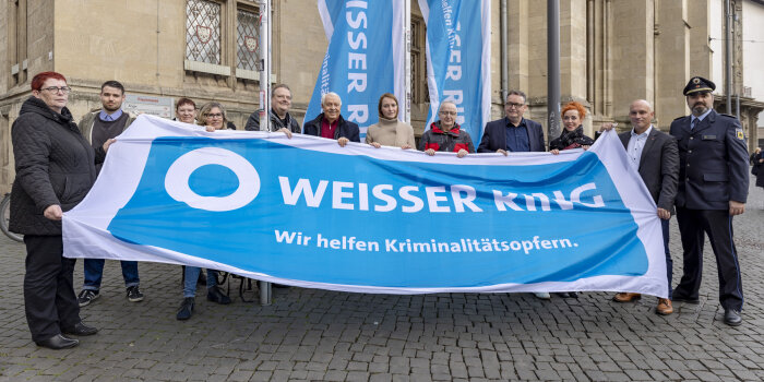 zwölf Personen halten eine Flagge des Weißen Rings