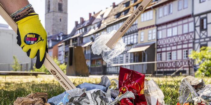 zwei Menschen picken Müll mit Holzgreifern