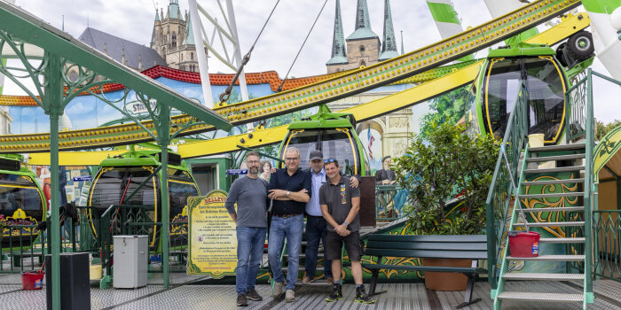 vier Männer stehen vor einem Riesenrad