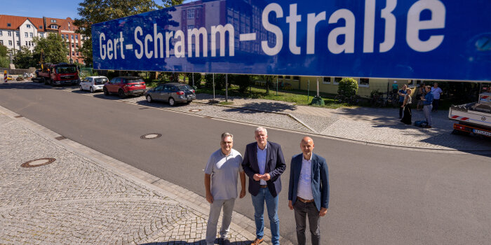 Drei Männerstehen unter einem Straßenschild