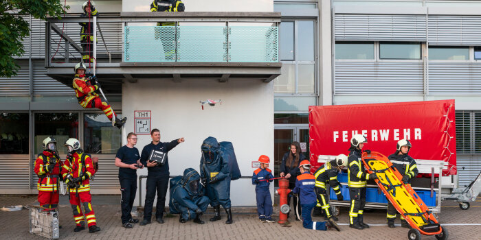 15 Erwachsene und Kinder posieren in ihren Feuerwehruniformen vor dem Gerätehaus.