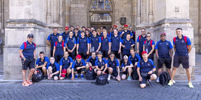 Eine Gruppe von Menschen in Sportsachen steht vor einem Rathaus.