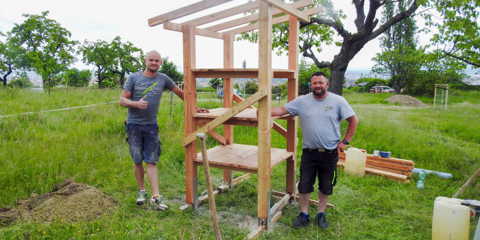 zwei Männer stehen an einem Holzgerüst