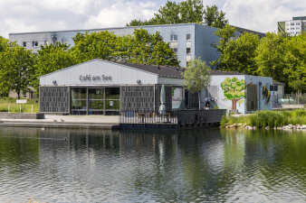 Foto: Öffentliche Toilette: Café am Auenteich © Stadtverwaltung Erfurt Ein Haus mit der Aufschrift „Café am See“. Davor ist der See zu sehen.