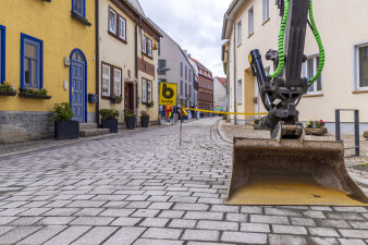 ein Bagger steht in einer frisch gepflasterten Straße
