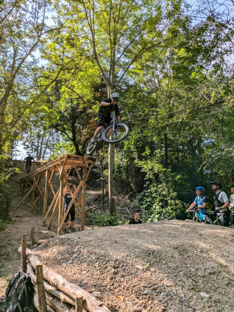 ein Mountainbiker in der Luft, nachdem er über eine Holzrampe gefahren ist