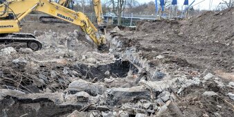 Ein Bagger zerlegt Betonteile im aufgewühlten Boden. 