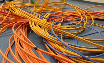 Gelbe, blaue und orangene Kabel liegen auf einem Boden. 