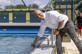 ein Mann im weißen Hemd hält die Hand in ein Schwimmbecken