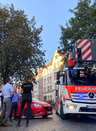 Mehrere Menschens stehen neben einem roten Auto und einer Feuerwehr