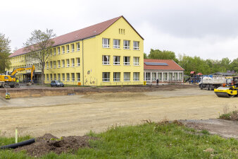 eine freie Baufläche vor einem dreistöckigen gelben Haus