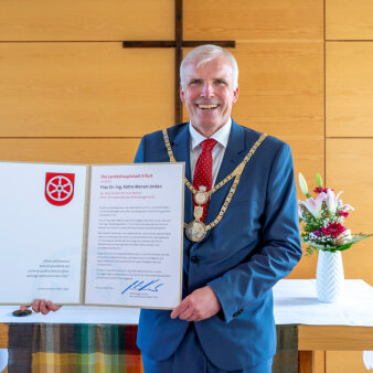 Ein Mann hält eine große Urkunde