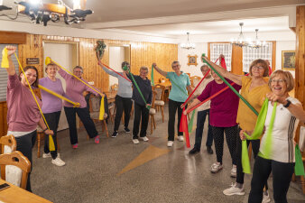 Zehn Frauen in Sportkleidung mit elastischen Fitnessbändern in der Hand