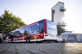 Auf dem Heck eines Busses steht: „Wir haben Aufnahmezustand“. Es wird um mehr Personal für die Feuerwehr geworben. 